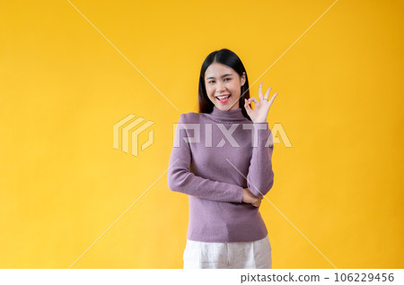 A beautiful Asian woman is showing the Okay hand sign, isolated yellow background. agree, perfect A beautiful Asian woman is showing the Okay hand sign, isolated yellow background. agree, perfect 106229456