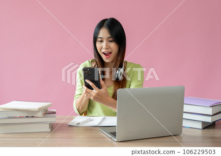 A beautiful Asian female college student is looking at her smartphone screen with a surprising face 106229503