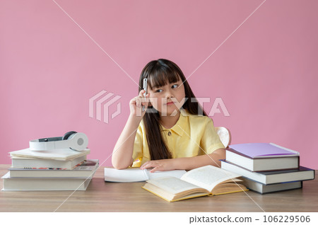 A girl is showing a thoughtful and thinking facial expression while sitting at her study table 106229506