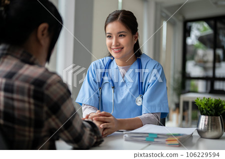 A caring Asian female doctor holds a patient's hands to reassure and comfort her feelings 106229594