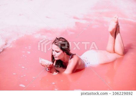 Woman in a pink salt lake. She lies in a white bathing suit. Wanderlust photo for memory 106229892