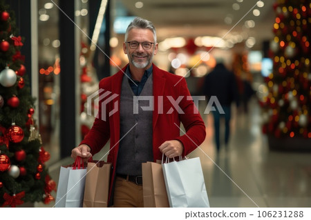 Photo of a middle aged smile man with a Christmas gifts in a shopping bags in a mall. Photo of a middle aged smile man with a Christmas gifts in a shopping bags in a mall. 106231288