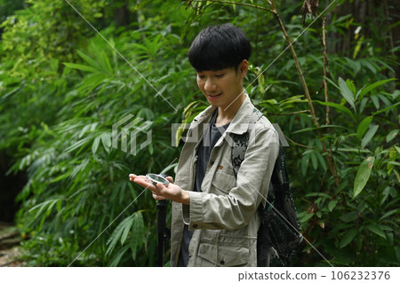 Male hiker using compass for directions in the forest, enjoying his active vacation Male hiker using compass for directions in the forest, enjoying his active vacation 106232376