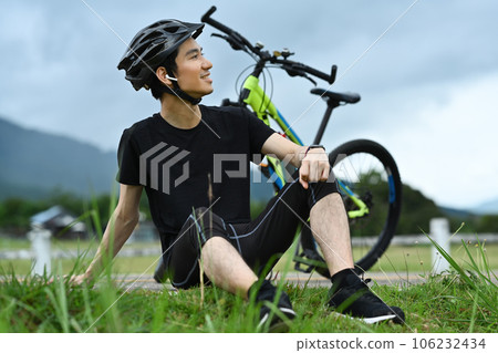Sporty asian man taking a break from cycling in a park. Active sporty and healthy lifestyle concept Sporty asian man taking a break from cycling in a park. Active sporty and healthy lifestyle concept 106232434