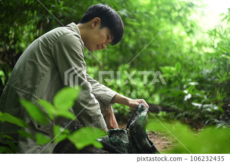 Man with backpack sitting on rocks resting during hiking in green forest. Traveling, trekking and adventure concept Man with backpack sitting on rocks resting during hiking in green forest. Traveling, trekking and adventure concept 106232435