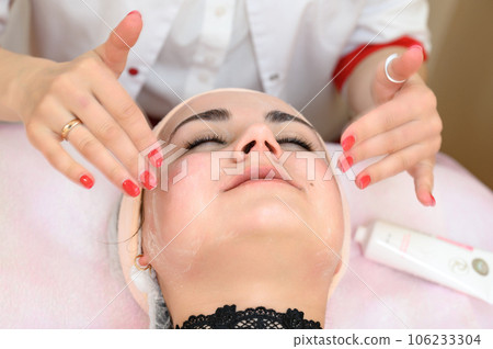 A beautician gives a relaxing face massage to a girl. A beautician gives a relaxing face massage to a girl. 106233304