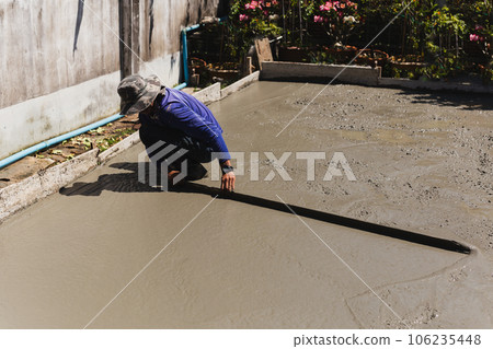 Workers level cement concrete concrete patio floor using long trowel. 106235448