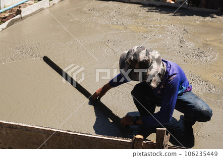 Workers level cement concrete concrete patio floor using long trowel. 106235449