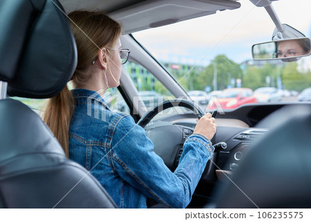 Teenage girl driver in glasses sitting behind wheel of car Teenage girl driver in glasses sitting behind wheel of car 106235575
