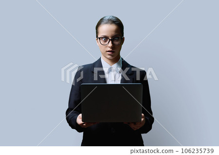 Serious teenage female student using laptop on grey background 106235739