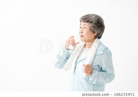 Senior woman drinking water after gymnastics 106235951