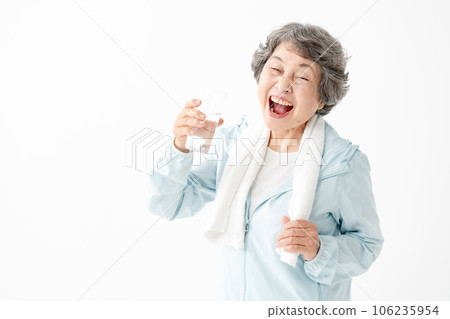 Senior woman drinking water after gymnastics 106235954