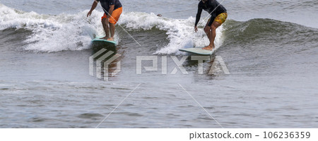 Two men surfing catching  the same wave 106236359