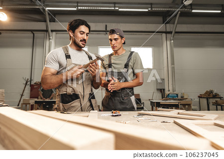 Two young men carpenters making furniture in warehouse of wood factory 106237045