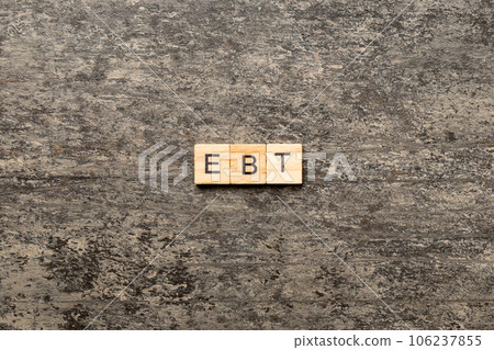 EBT word written on wood block. Abbreviation Earnings Before Taxes text on cement table for your desing, concept 106237855