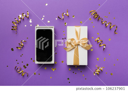 Opened gift box with gold ribbon and smartphone on color background, top view. Blank open box packaging mockup , Template for your design - branding mockup Opened gift box with gold ribbon and smartphone on color background, top view. Blank open box packaging mockup , Template for your design - branding mockup 106237901