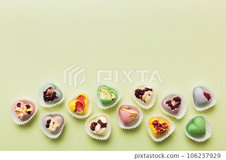 chocolate sweets in the form of a heart with fruits and nuts on a colored background. top view with space for text, holiday concept chocolate sweets in the form of a heart with fruits and nuts on a colored background. top view with space for text, holiday concept 106237929
