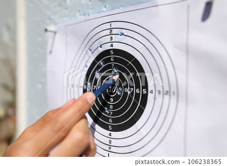 Man showing with pencil to shots on paper target closeup 106238365