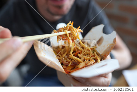 Cardboard box with seafood noodles wooden chopsticks closeup Cardboard box with seafood noodles wooden chopsticks closeup 106238561