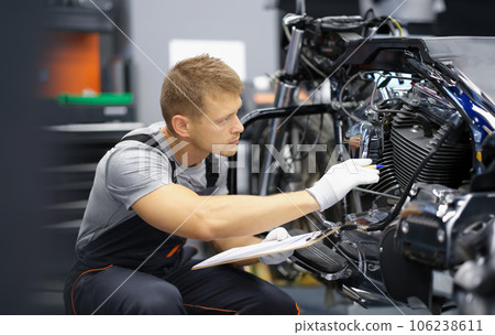 A man in the garage is checking a motorcycle 106238611