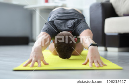 Young man is doing exercises to stretch his back muscles Young man is doing exercises to stretch his back muscles 106238617