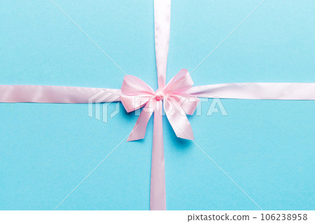 Top view of purple ribbon rolled and pink bow isolated on colored background. Flat lay with copy space Top view of purple ribbon rolled and pink bow isolated on colored background. Flat lay with copy space 106238958