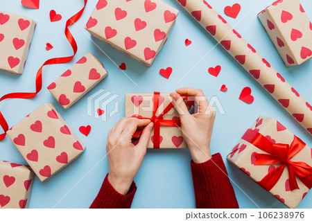 Women hands pack gifts and make decorations for the holiday, top view. Birthday and valentine present Women hands pack gifts and make decorations for the holiday, top view. Birthday and valentine present 106238976