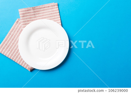Top view on colored background empty round white plate on tablecloth for food. Empty dish on napkin with space for your design Top view on colored background empty round white plate on tablecloth for food. Empty dish on napkin with space for your design 106239000