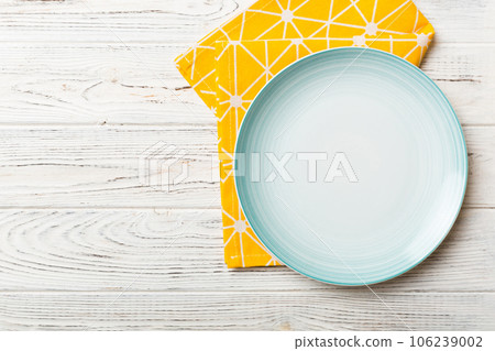 Top view on colored background empty round blue plate on tablecloth for food. Empty dish on napkin with space for your design Top view on colored background empty round blue plate on tablecloth for food. Empty dish on napkin with space for your design 106239002
