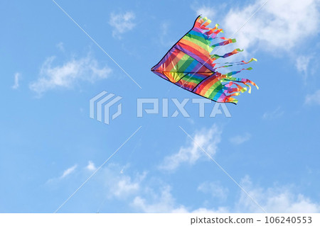 Kite in a blue sky. Rainbow Delta Kite flying among the clouds. Happy growing years moment. Outdoor time spending. Aspirations, target, inspiration concept. Freedom and summer holiday. Childhood dream 106240553