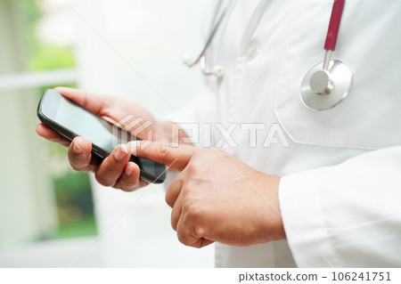 Asian woman doctor holding mobile phone or tablet for search method of treatment patient in hospital. 106241751