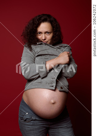 Attractive African American young pregnant woman with naked belly, wearing stylish casual denim blazer and jeans 106242072