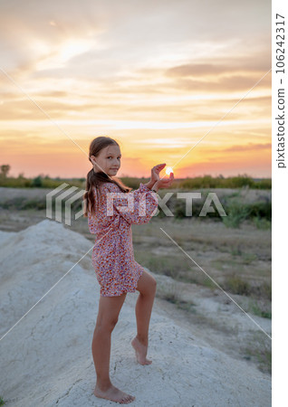 A teenage girl in a summer dress is photographed at sunset A teenage girl in a summer dress is photographed at sunset 106242317