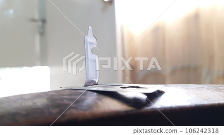 closeup view of single stainless steel mosquito repellent coil stand isolated on brown wooden background 106242318