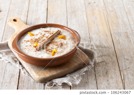 Arroz con leche. Rice pudding with cinnamon in clay bowl on wooden table Arroz con leche. Rice pudding with cinnamon in clay bowl on wooden table 106243067