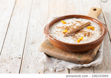 Arroz con leche. Rice pudding with cinnamon in clay bowl on wooden table 106243069