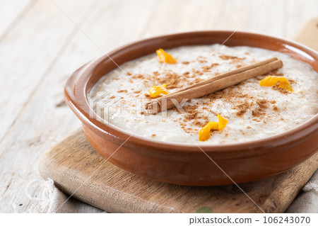 Arroz con leche. Rice pudding with cinnamon in clay bowl on wooden table 106243070