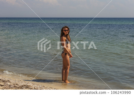a girl in a swimsuit and sunglasses stands on the beach a girl in a swimsuit and sunglasses stands on the beach 106243990