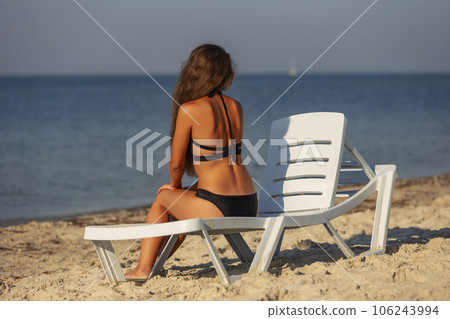 girl sitting on a sunbed near the sea girl sitting on a sunbed near the sea 106243994