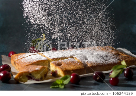 Powdered sugar decorates sponge cake with a cherry Powdered sugar decorates sponge cake with a cherry 106244189
