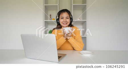Beautiful young asian woman enjoy drinking coffee and listening to music with headphone at desk home, happiness and relaxation concepts 106245291