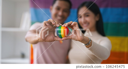 A charming and cheerful Asian gay radio host enjoys chatting while recording an audio podcast with his female friend with a rainbow flag in the background A charming and cheerful Asian gay radio host enjoys chatting while recording an audio podcast with his female friend with a rainbow flag in the background 106245475