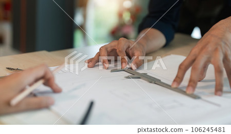 Closeup hand of engineer team with construction work plan discussion together blueprint on working table in construction site with safety helmet Closeup hand of engineer team with construction work plan discussion together blueprint on working table in construction site with safety helmet 106245481