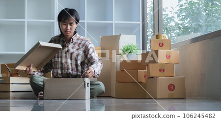Young asian man smiling confident unpacking cardboard box at new home 106245482