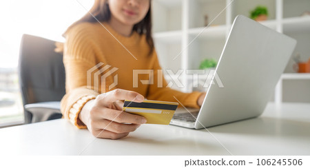 Closeup asian woman holding credit card and smartphone, sitting at home, happy satisfied young female customer shopping online 106245506