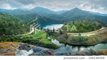 Abandoned mining area restoration in Cyprus. Panorama of open pit Memi sulphides mine with pit lake and colourful mine tailings on the foreground 106246499