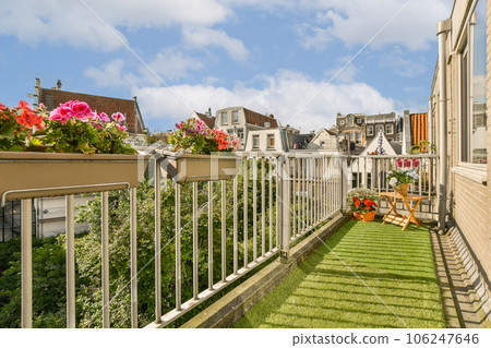 a balcony with flowers on the railings and green grass in the foreground is bright blue sky above it 106247646