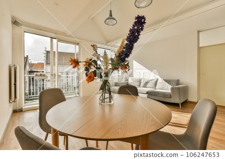 a dining table and chairs in a living room with an open window looking out onto the cityscapea 106247653