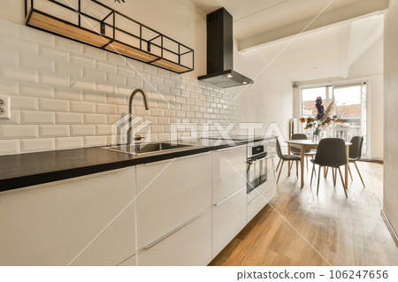 a kitchen with white tiles on the wall and wood flooring in the center of the room is a dining table 106247656