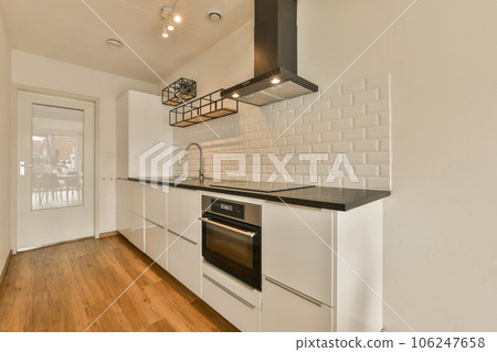 a kitchen with white tiles on the walls and wood flooring in front of the stove, oven and dishwasher a kitchen with white tiles on the walls and wood flooring in front of the stove, oven and dishwasher 106247658